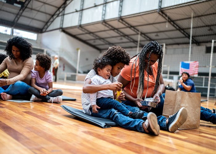 Children sitting on a gym floor, engaging with a tablet.