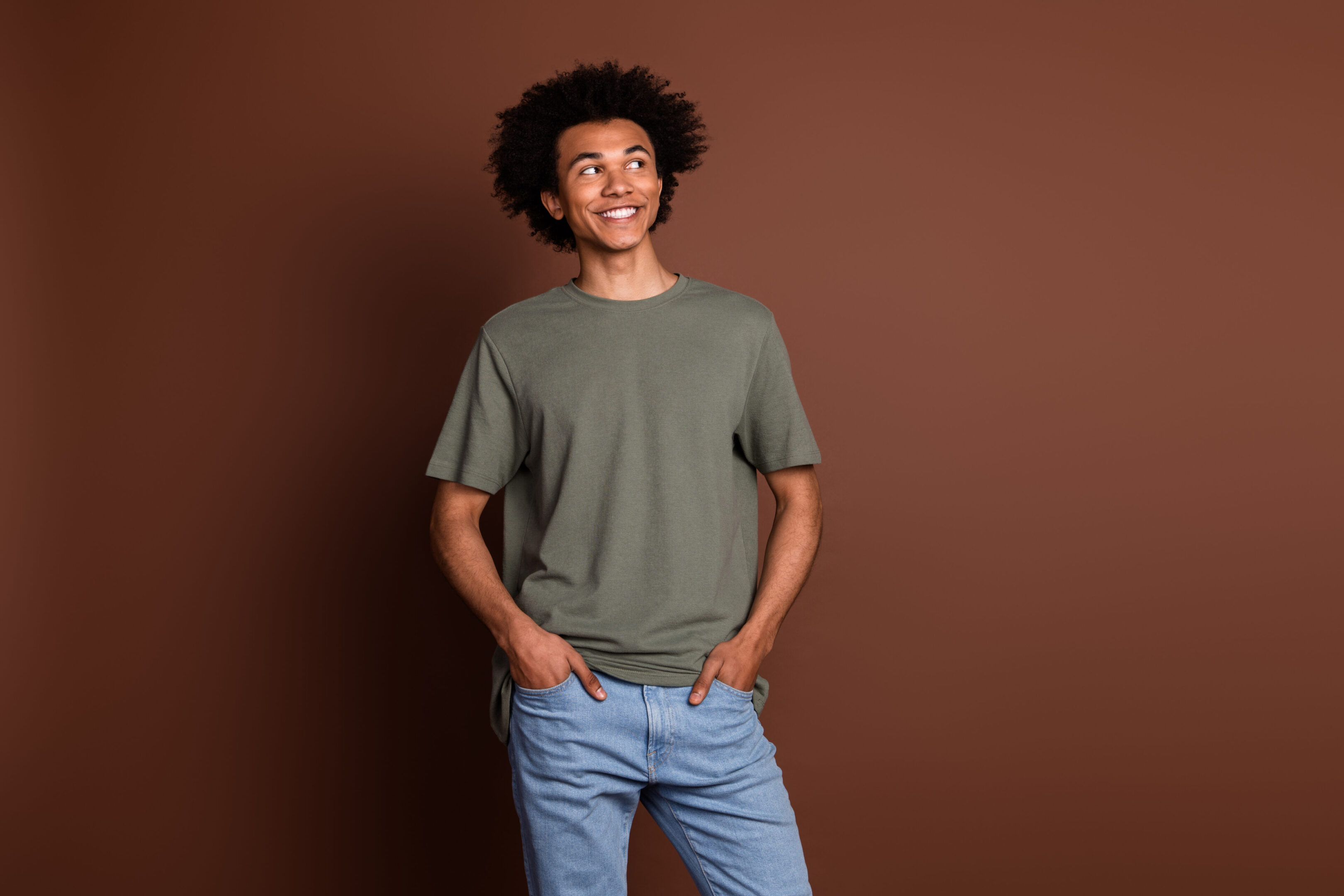 Smiling person in casual clothes, brown background.
