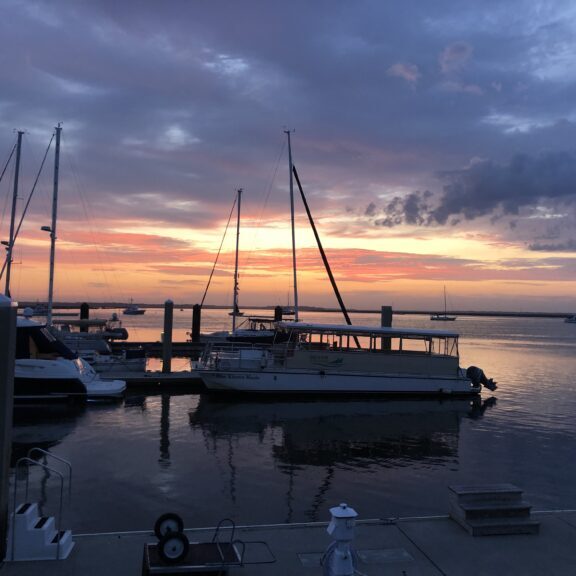 Boats docked at marina during sunset