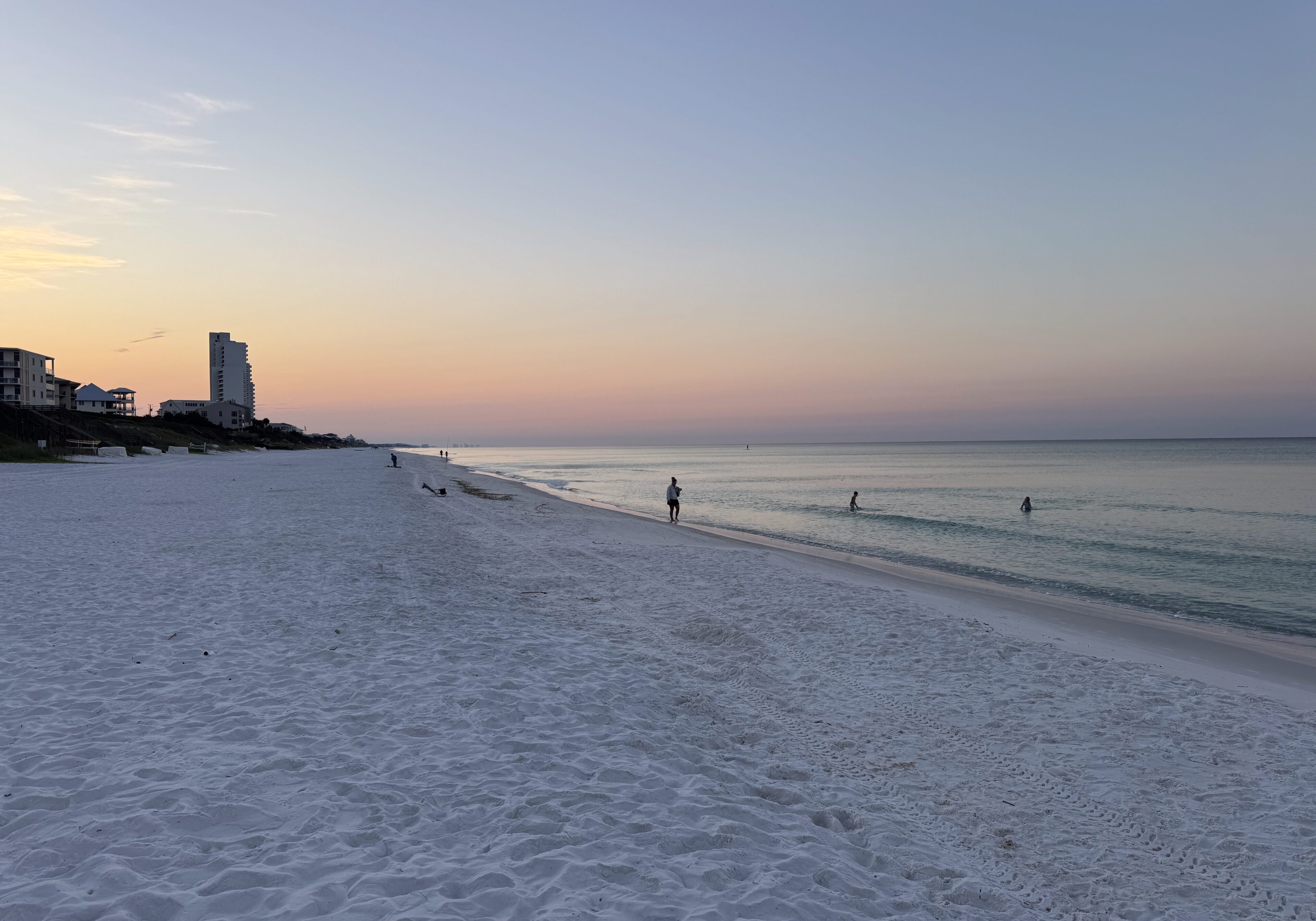 A peaceful beach scene at sunset with a lone figure near the water.