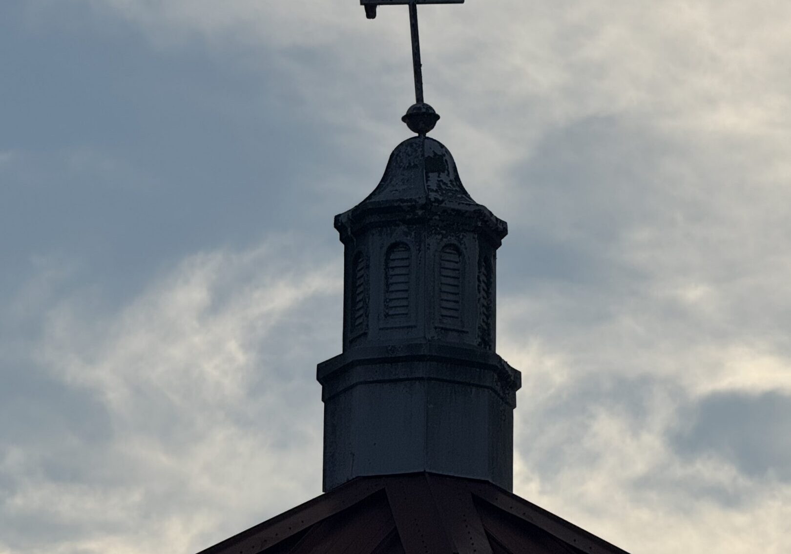 Bird perched on cross atop church steeple